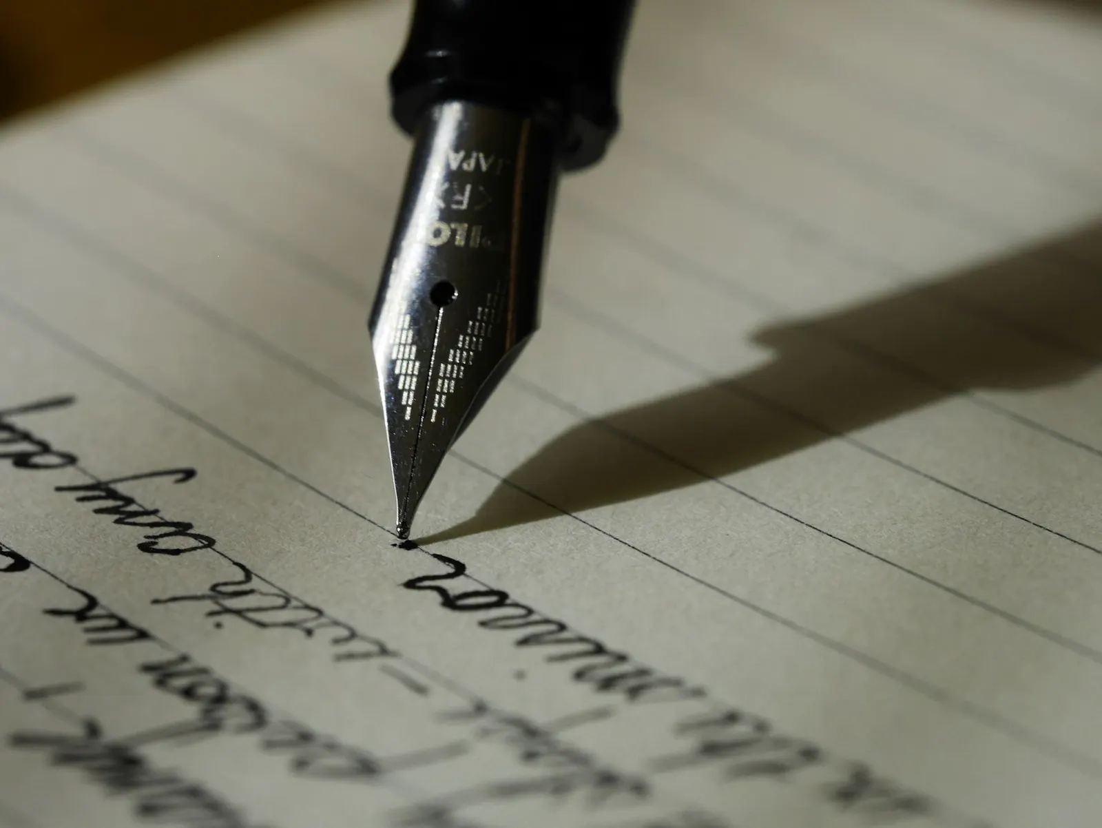 A fountain pen writing across a lined page